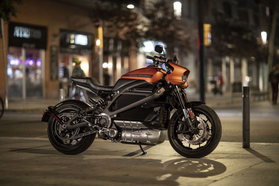 An orange-and-black 2021 Harley-Davidson LiveWire parked on a city street at night