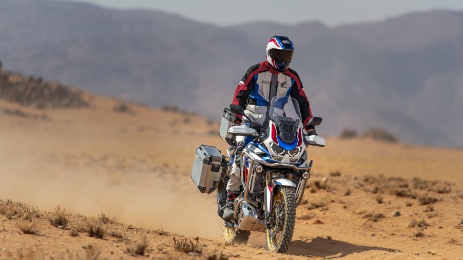 A white-red-and-blue-clad rider takes a white-red-and-blue 2021 Honda Africa Twin DCT through the desert