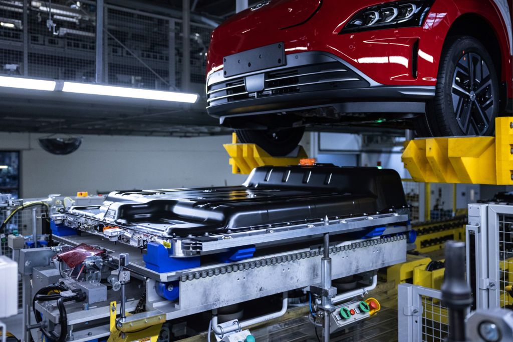 A red 2021 Hyundai Kona Electric body meets its battery pack during factory assembly