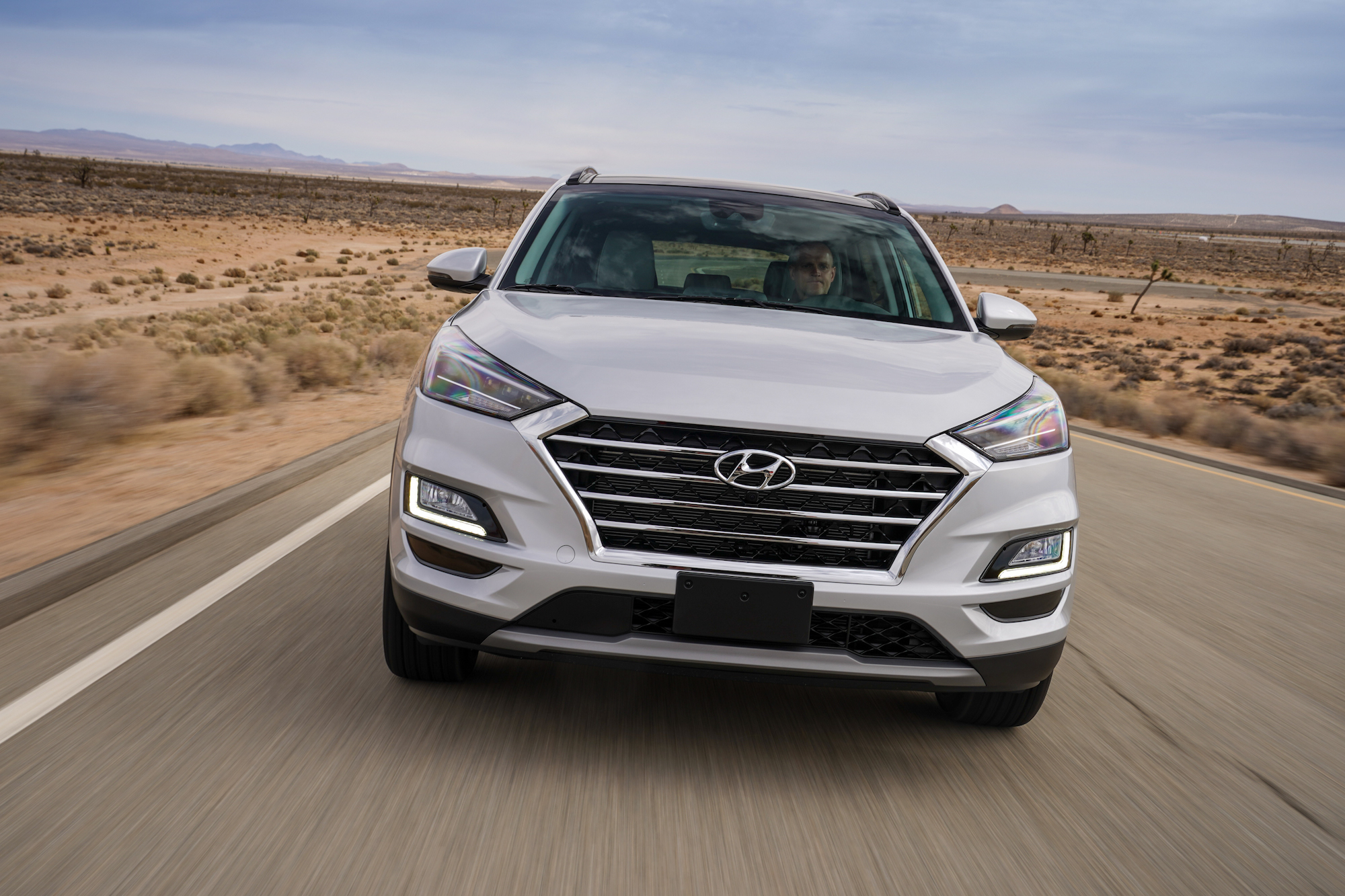 A white 2021 Hyundai Tucson compact crossover SUV traveling on a desert highway