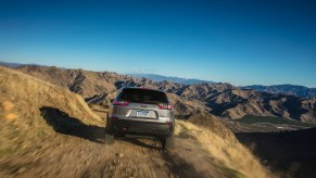 A rear view of a 2021 Jeep Cherokee Trailhawk traveling over gravel on a mountain