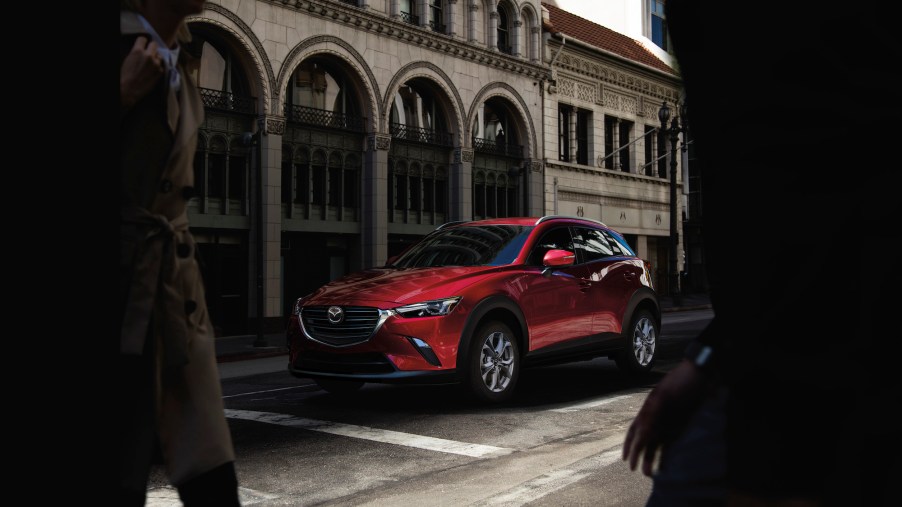 A red 2021 Mazda CX-3 Sport crossover SUV parked outside a stone building with arched windows