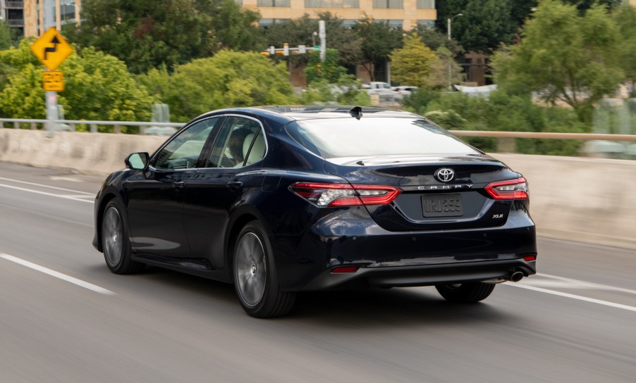 A navy blue 2021 Toyota Camry midsize sedan traveling on a city highway