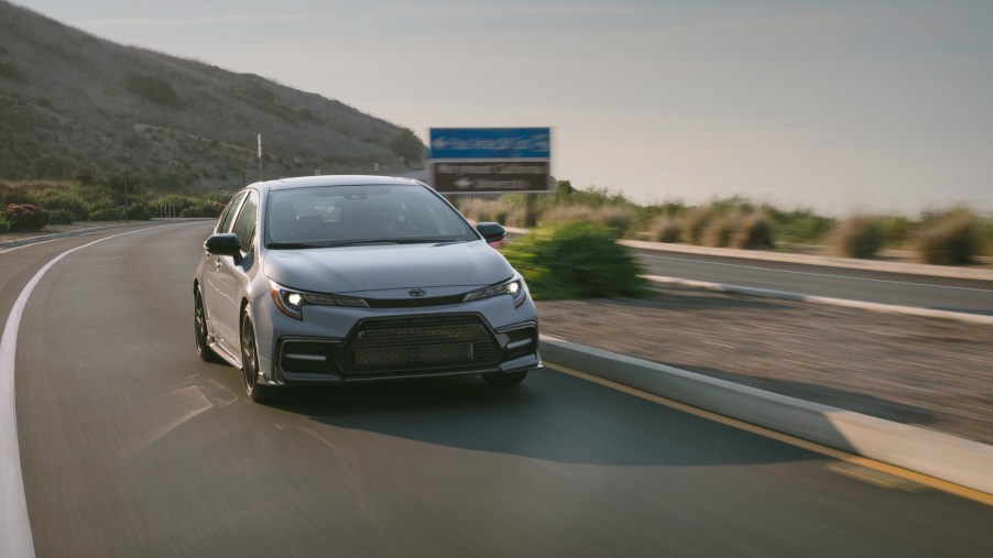 A silver 2021 Toyota Corolla Apex compact car cornering on a mountain highway