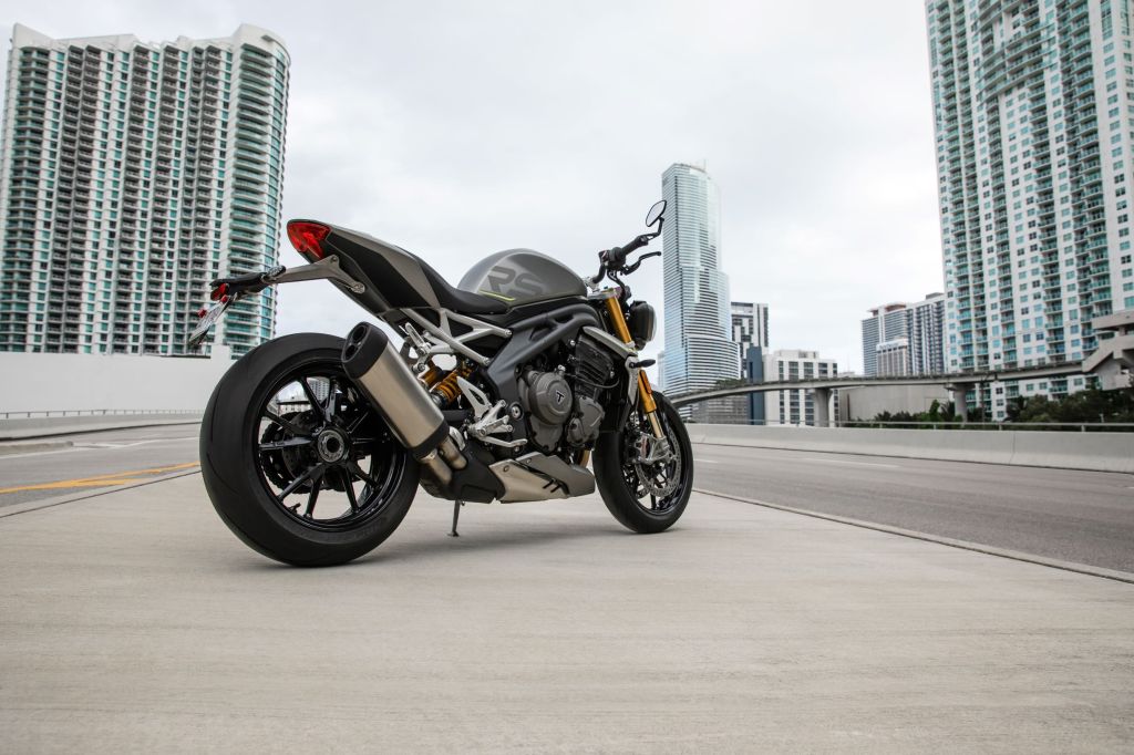 The rear 3/4 view of a gray-and-black 2021 Triumph Speed Triple 1200 RS on a city street
