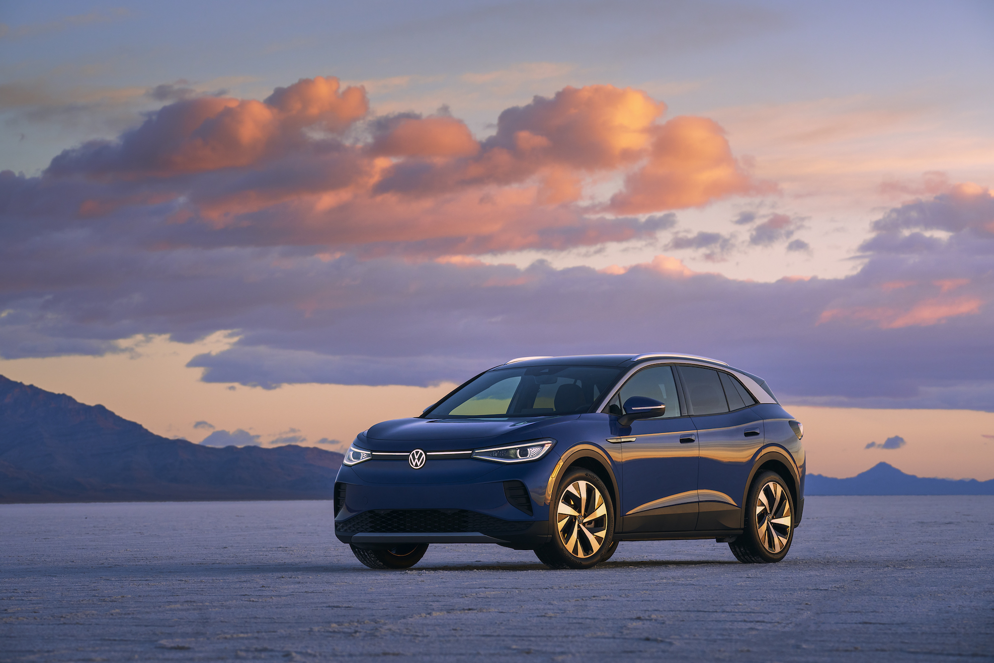 A blue 2021 Volkswagen ID.4 electric SUV parked in a desert at sunset