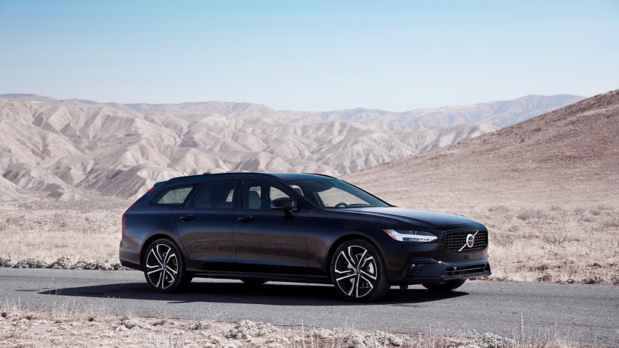 A black 2021 Volvo V90 station wagon parked on paved road through desert mountains