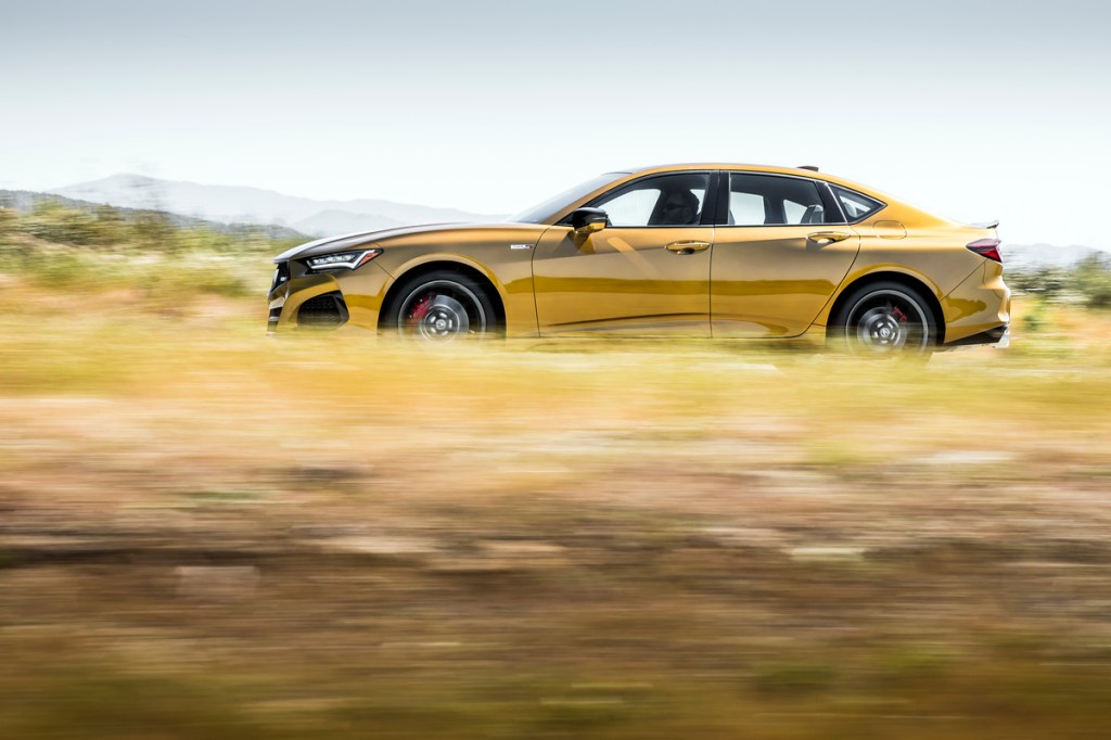 A gold TLX Type S flies by with a blurred foreground and background