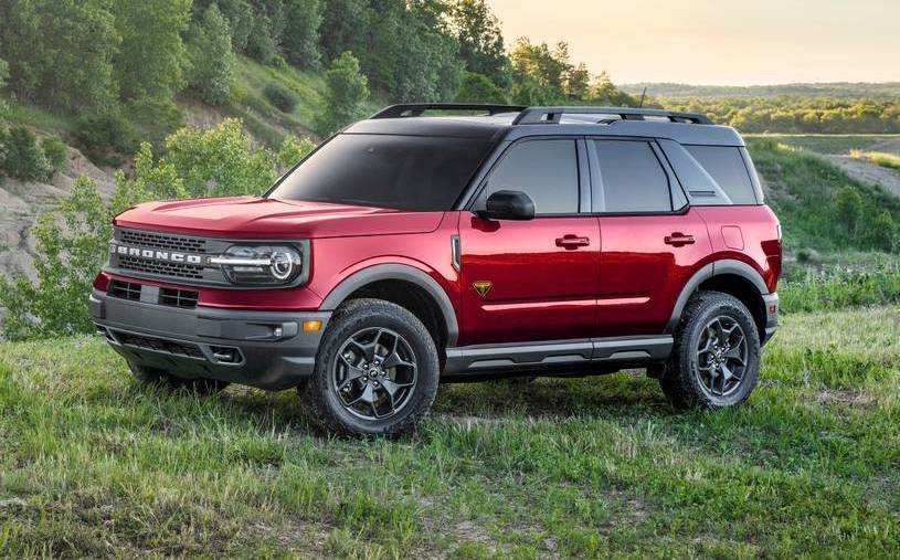 A red 2021 Ford Bronco Sport parked in a field filled with green grass