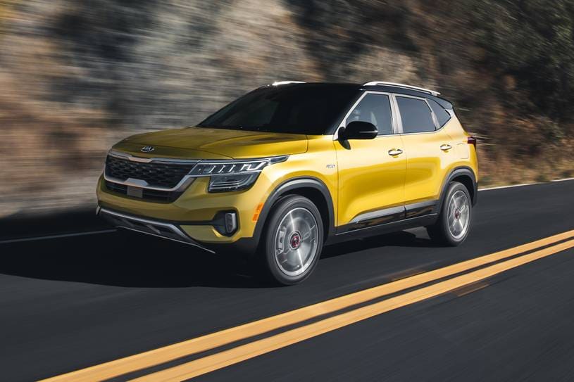 A yellow 2021 Kia Seltos driving quickly down the road