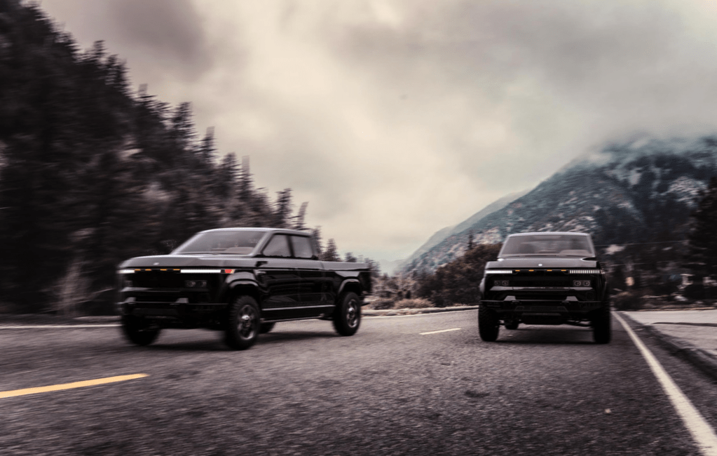 A pair of 2022 Atlis XT pickup trucks driving down a mountain road