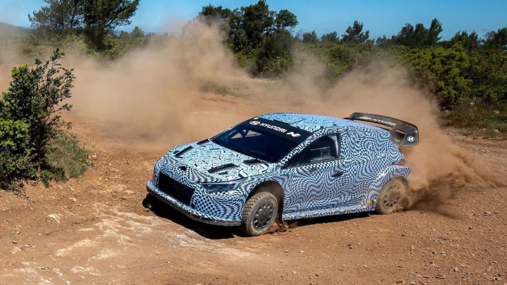 The side view of the blue-and-white-camouflaged 2022 Hyundai i20 N Rally1 prototype drifting on a gravel rally stage
