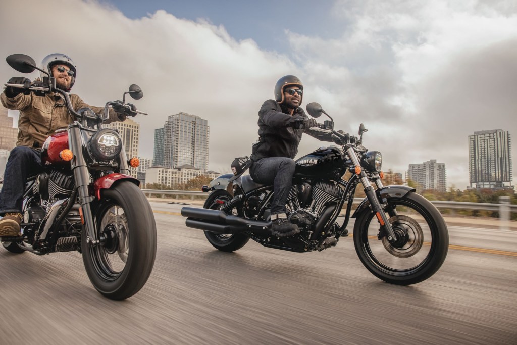 A black and a red 2022 Indian Chief riding down a damp city highway