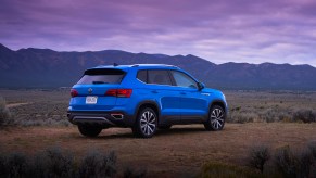 A bright-blue 2022 Volkswagen Taos compact SUV parked on a plain overlooking mountains