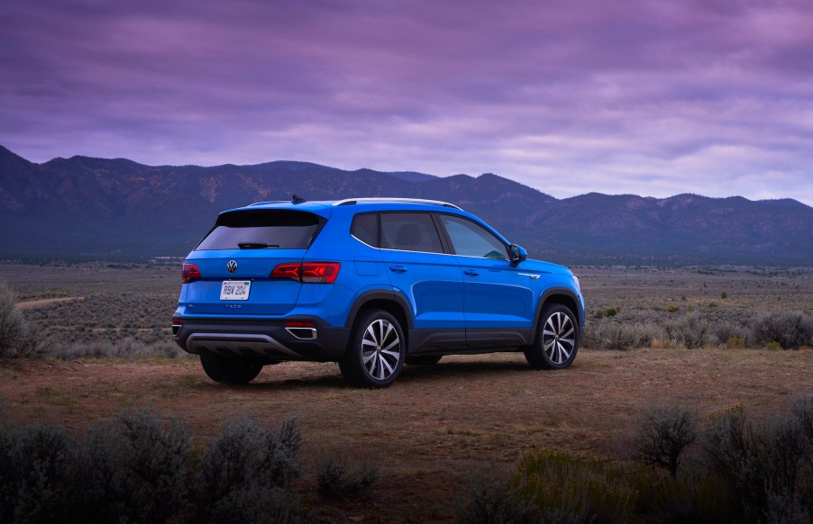 A bright-blue 2022 Volkswagen Taos compact SUV parked on a plain overlooking mountains