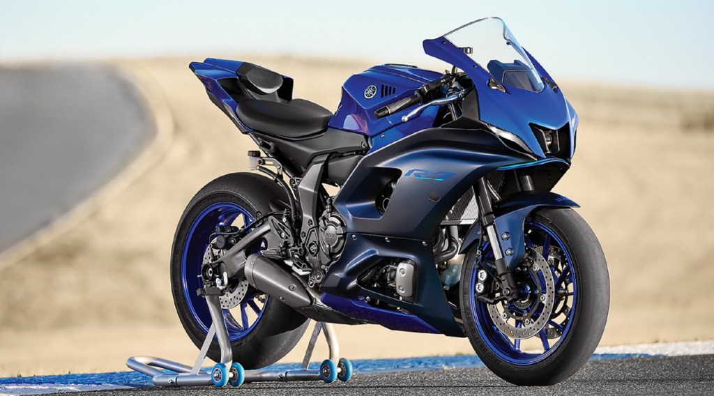 A blue-and-black 2022 Yamaha YZF-R7 on a rear-wheel stand on a desert racetrack