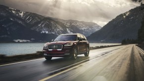 The 2021 Lincoln Aviator PHEV driving down a road near water and mountains