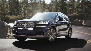 The 2021 Lincoln Aviator driving on a curvy road through the forest