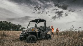 People in orange vests hunting in a field with a dog and the Polaris Ranger EV