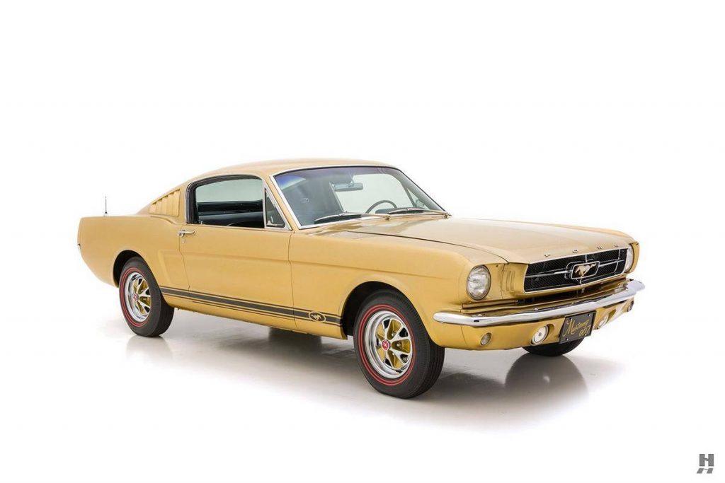 An image of a gold Ford Mustang parked inside of a photo studio.