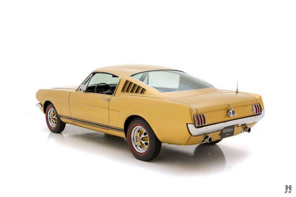 An image of a gold Ford Mustang parked inside of a photo studio.