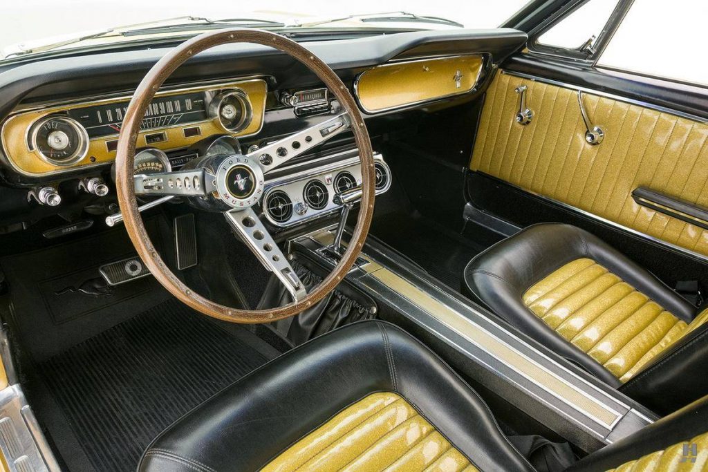 An image of a gold Ford Mustang parked inside of a photo studio.