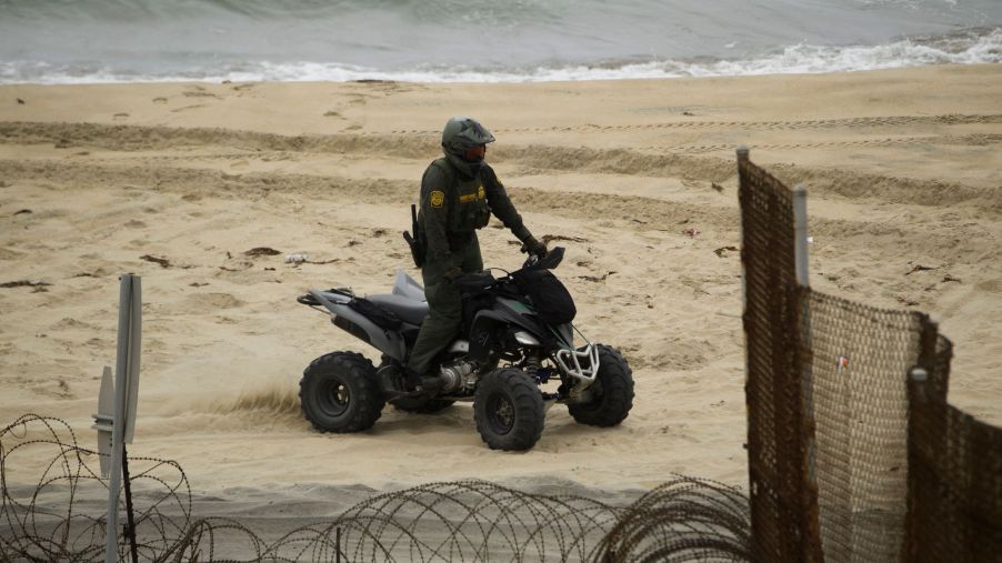 A U.S. Border Patrol agent drives an ATV on the beach next to the Pacific Ocean