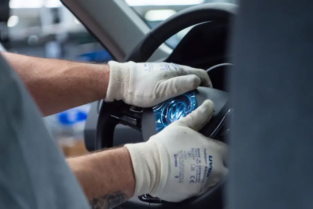 An employee assembles an airbag with a steering wheel