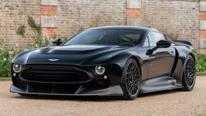 The Aston Martin Victor sits on gravel in front of a brick wall