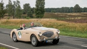 A beige Austin Healey driving on the open road