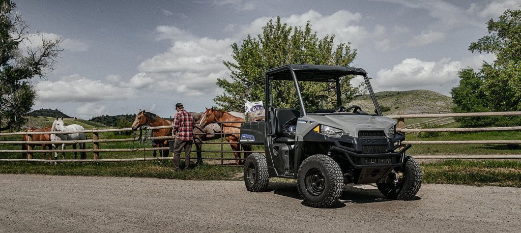 The Polaris Ranger EV parked near a corral of horses on a ranch 