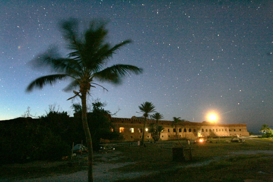 A breeze sways the fronds of a coconut palm as dusk brings out the stars over Fort Jefferson on Garden Key in Dry Tortugas National Park, Florida