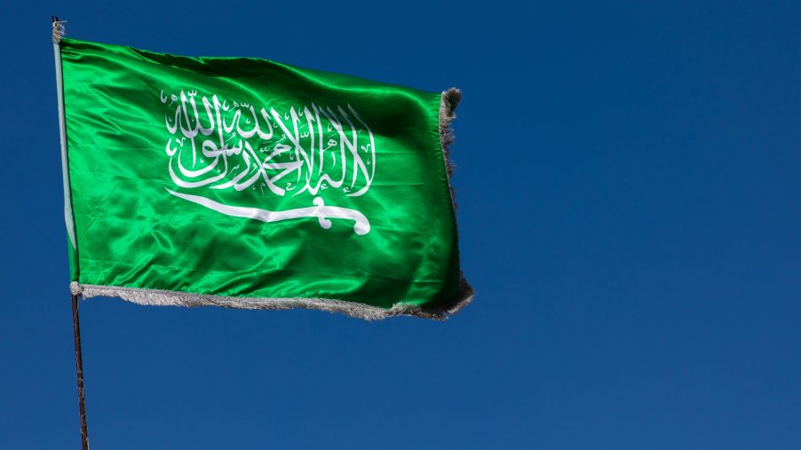 Emerald green flag of Saudi Arabia against a blue sky