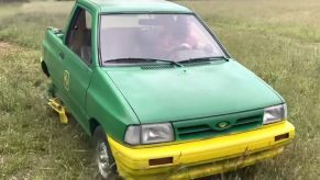 A green and yellow Ford Festiva compact car modified into a lawnmower