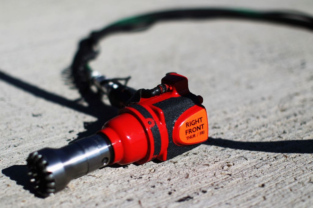 A red-black-and-orange Formula 1 wheel nut gun laying on the ground