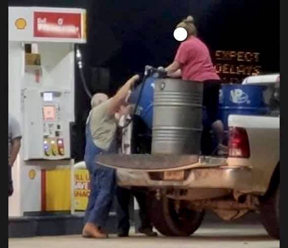 filling up oil barrels with gasoline
