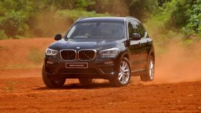 a BMW X3 variant driving off-road in red sand.