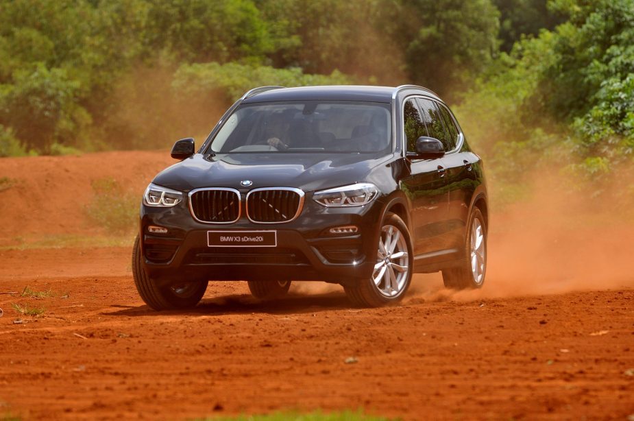 a BMW X3 variant driving off-road in red sand.