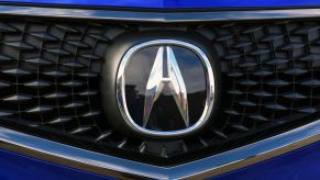 The Acura badge sitting on the grille of a blue TLX
