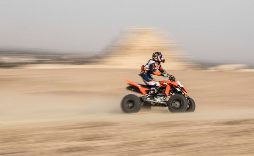 an ATV rider on a quad riding fast in the desert