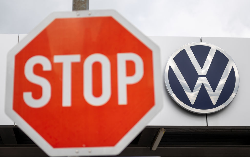 A stop sign in front of the Volkswagen logo on a white building