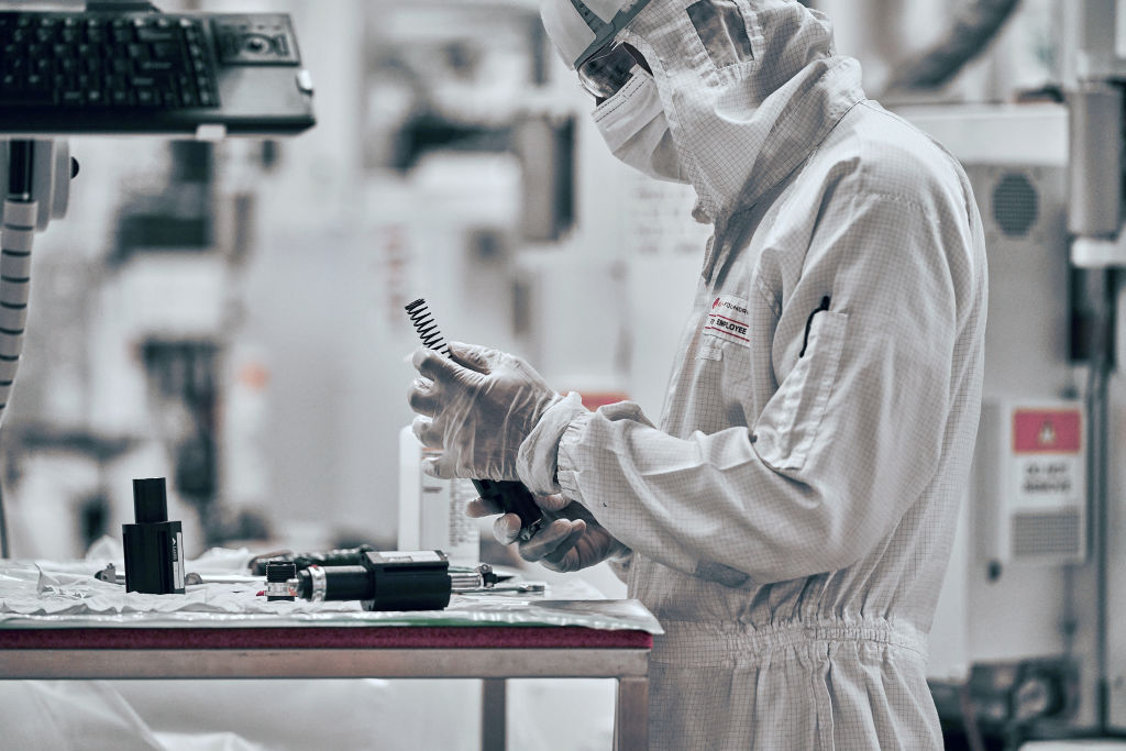 A man works in a lab, wearing protective garb while producing semiconductors.