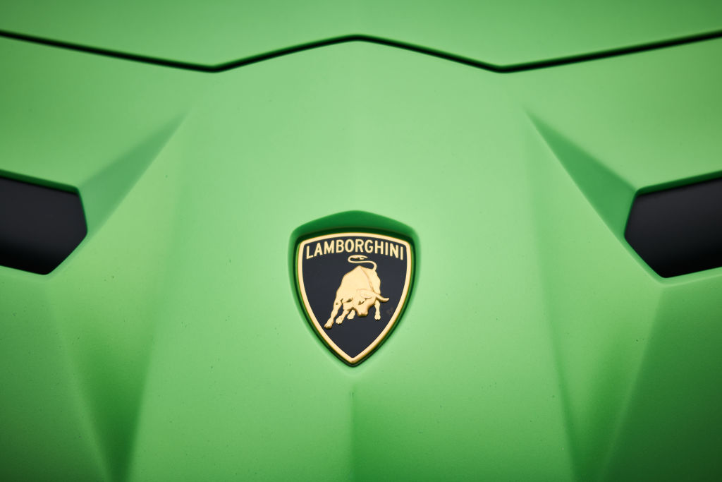 closeup shot of Lamborghini logo on hood of green Aventador