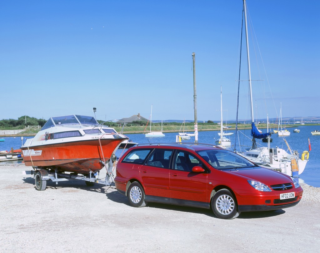 A red Citroen C5 HDI towing a boat