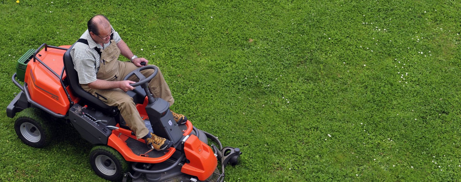 a man mowing a pristine lawn with a lawn tractor