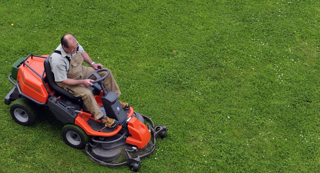 a man mowing a pristine lawn with a lawn tractor