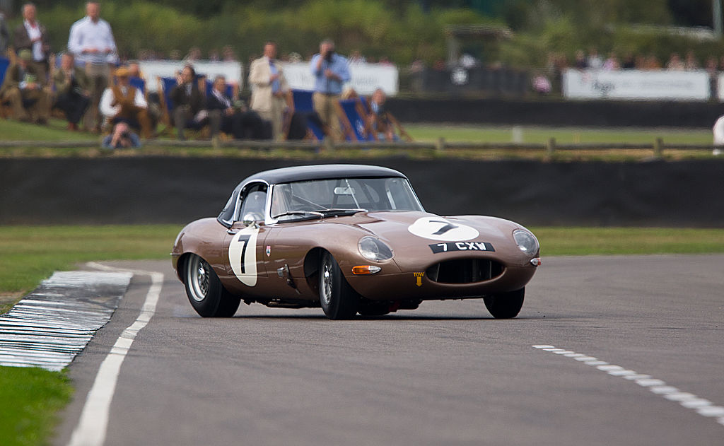 A brown Jaguar E-Type- not equipped with stability control- slides around a corner on a race track