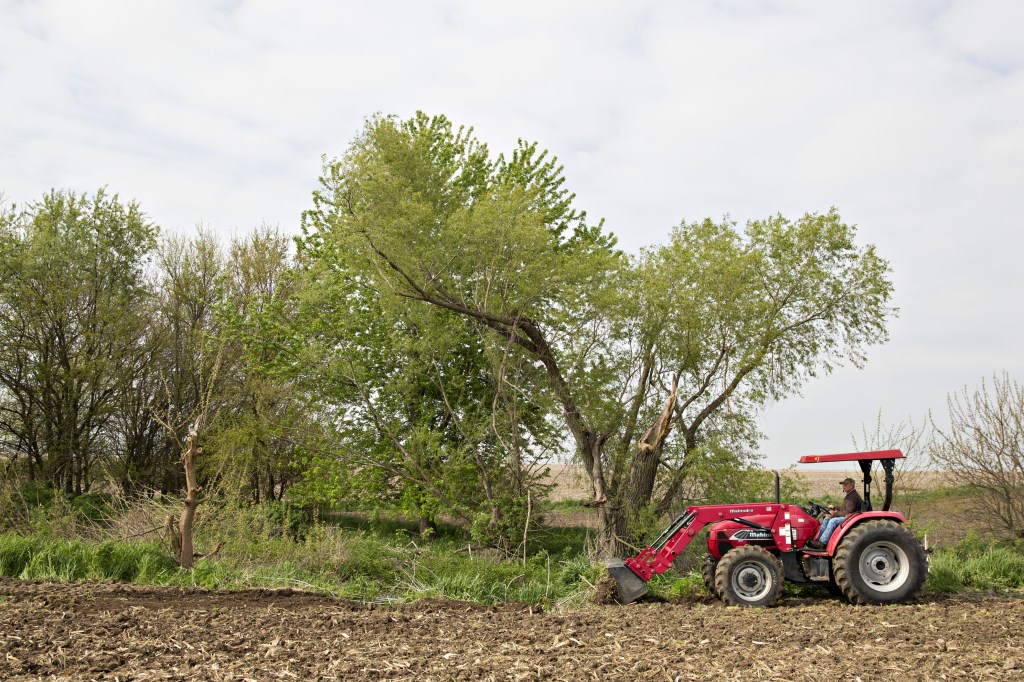 a red Mahindra tractor preparing a field for corn planting