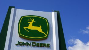 a John Deere logo on a tall sign with blue cloudy skies