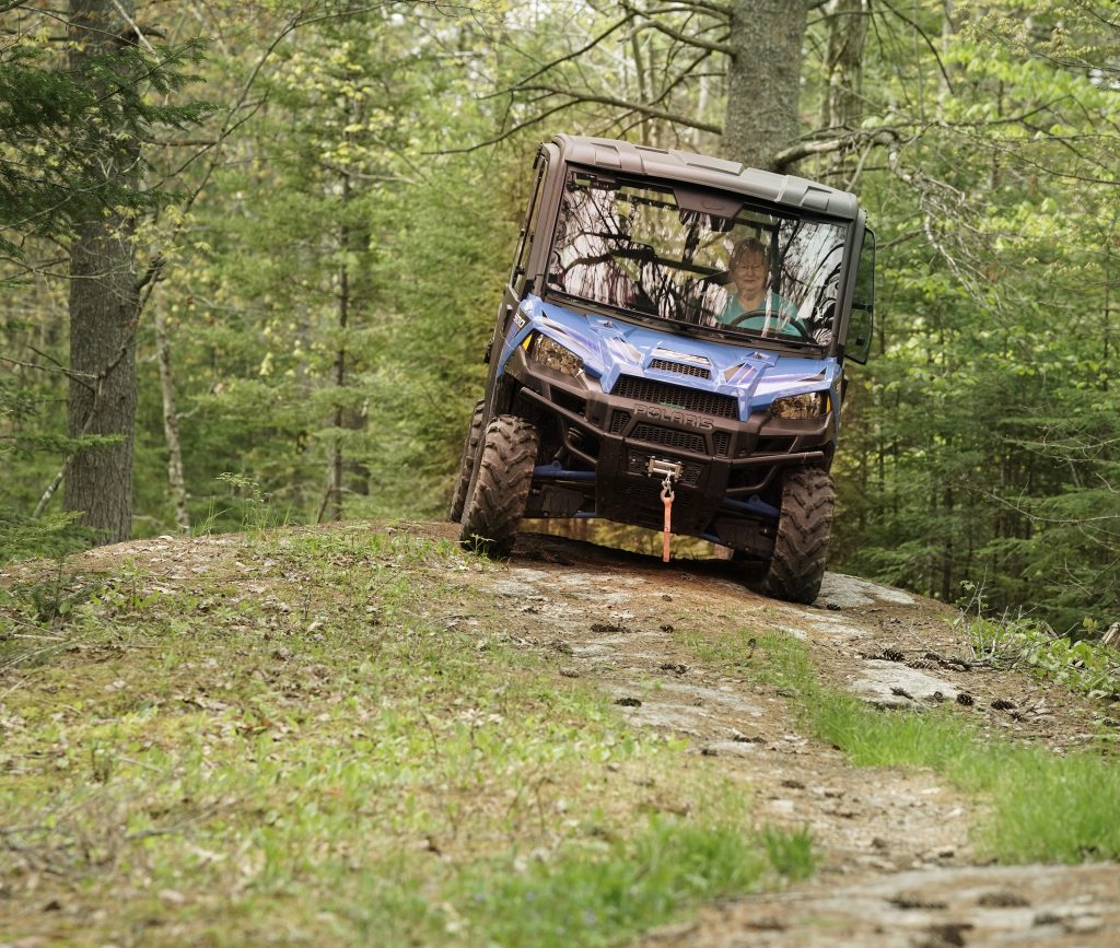 a blue Polaris Ranger in the forest 